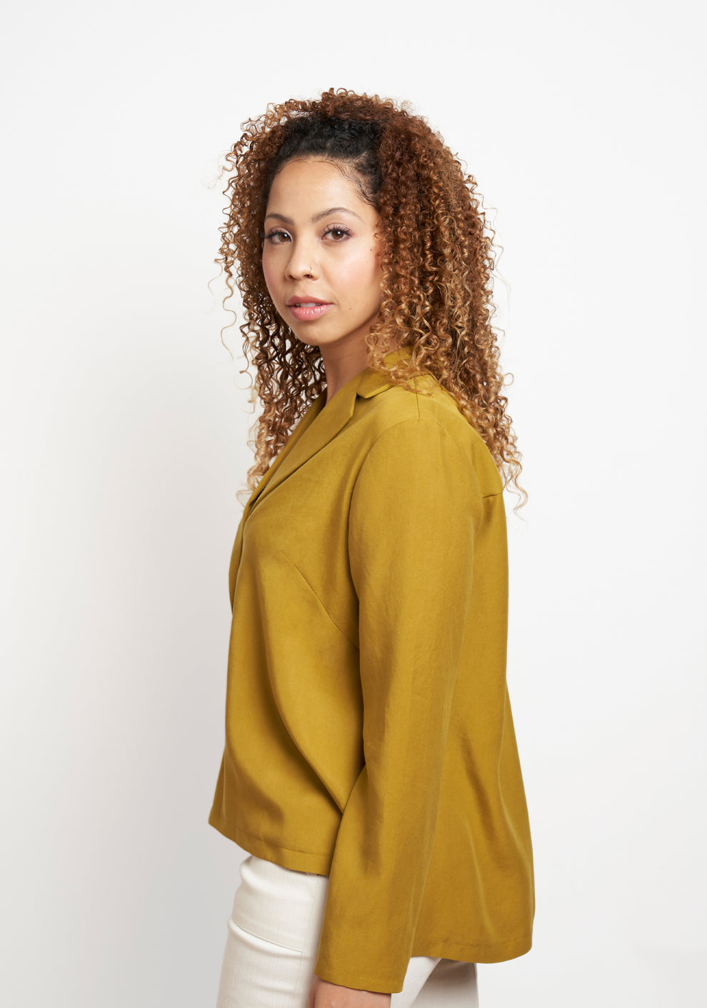 Side view of mustard long-sleeve Augusta Top, showing angled side seam and relaxed silhouette.