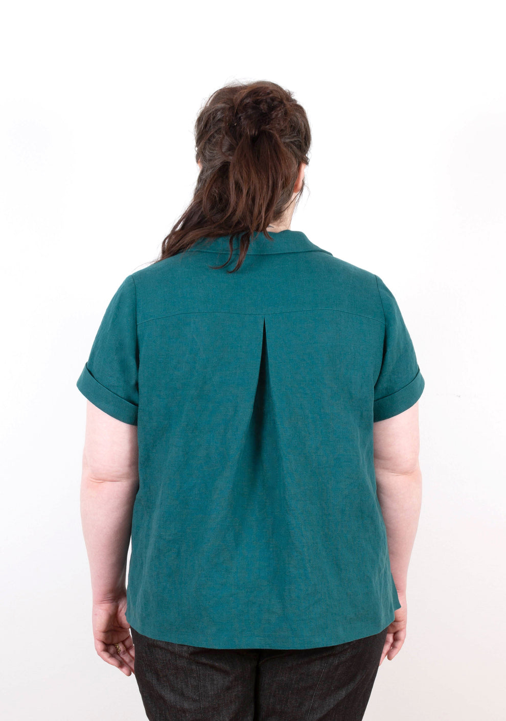Back view of Augusta Top showing center back pleat, yoke detail, and cuffed short sleeves.