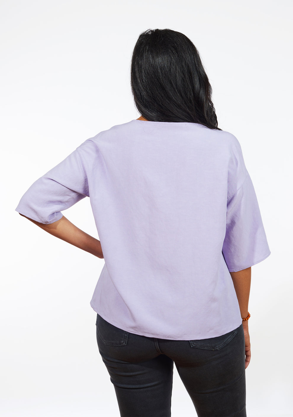Back view of lilac Corin Top showing curved hem and drop shoulder sleeve construction.