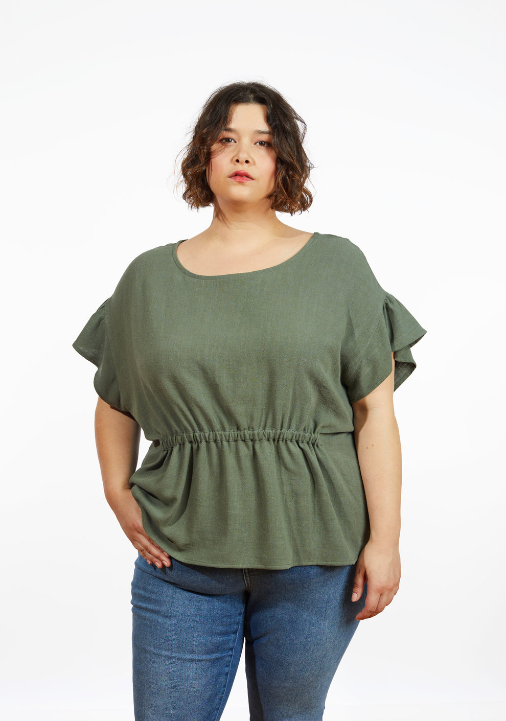 Model: Size 24, 5'5" | Corin Top in olive linen with relaxed fit, elastic waist, and drop shoulder flounce sleeves, front view on model.
