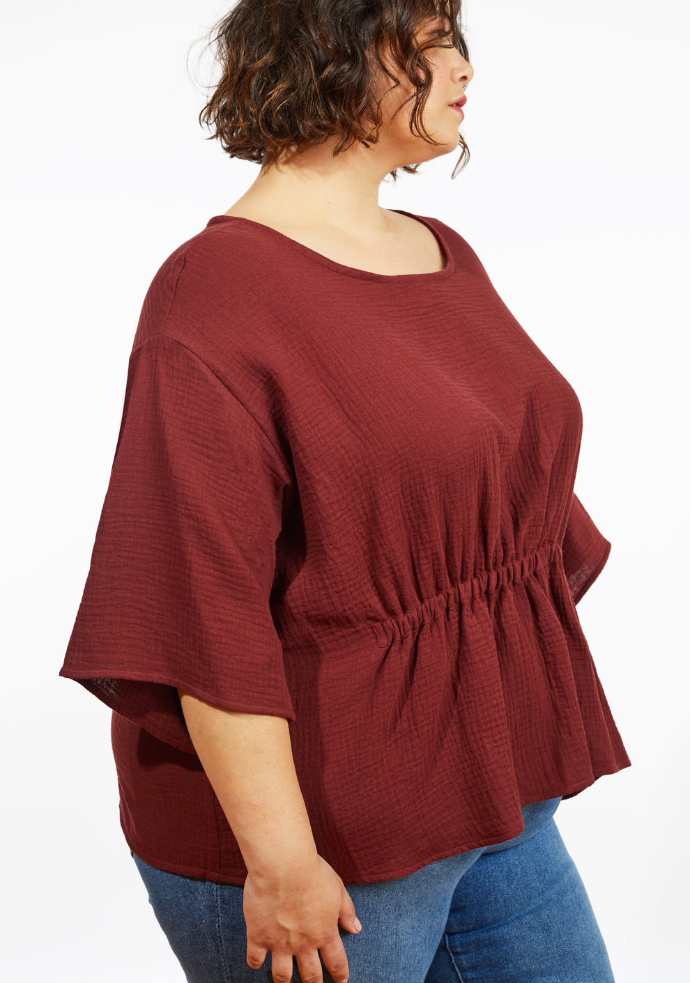 Side view of Corin Top in brick double gauze with elbow-length sleeve and gathered elastic waist on model.