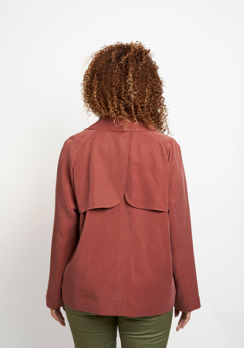 Back view of Cortland Trench View B in rust fabric, showing curved storm flaps.