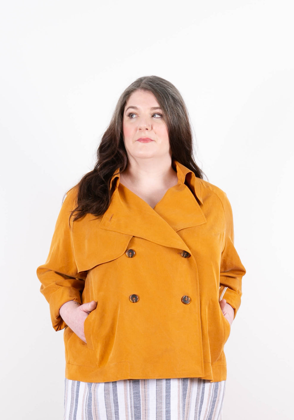 Model in golden Cortland Trench with hands in pockets, looking off camera.