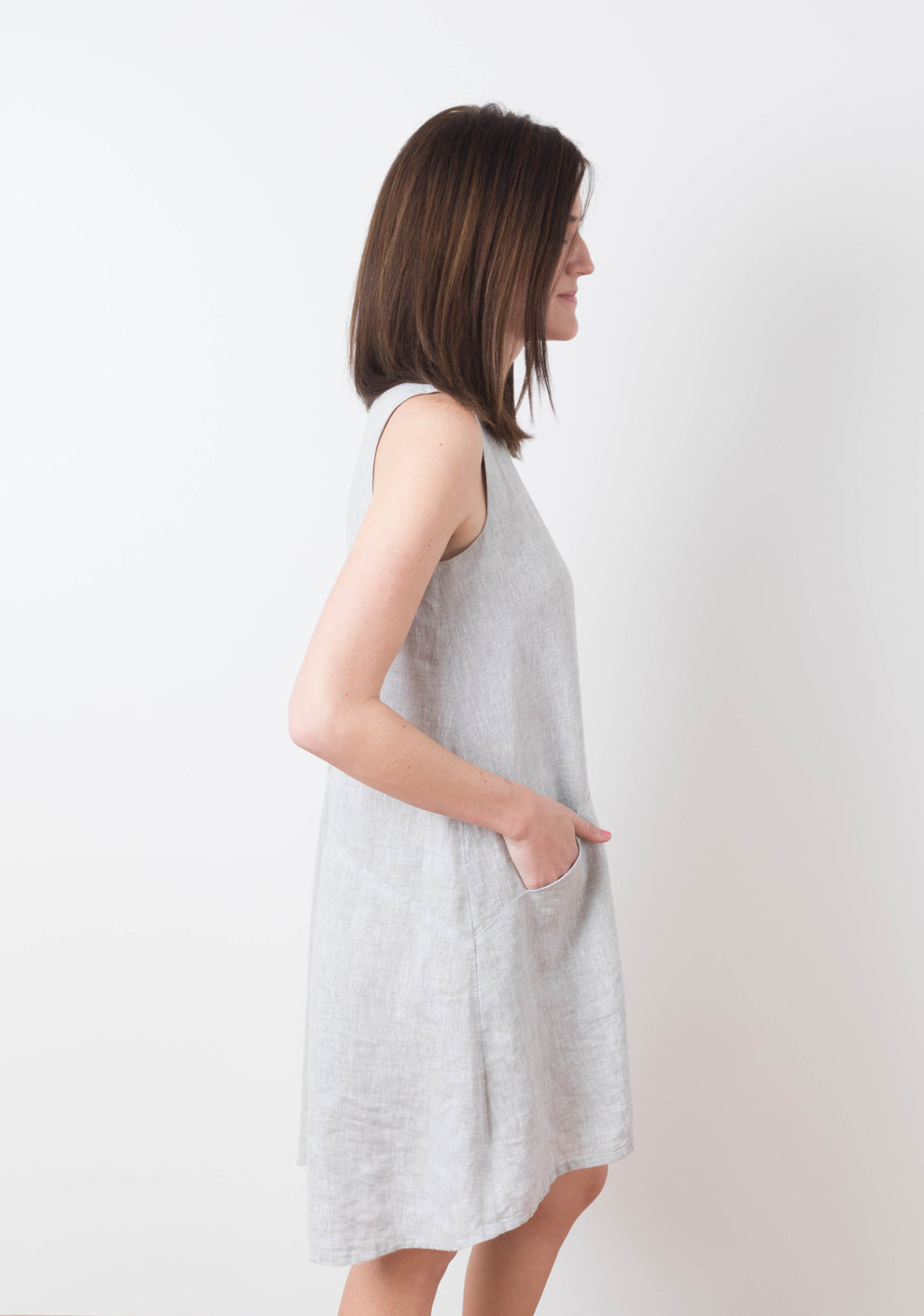 Side view of model wearing sleeveless Farrow Dress in solid grey linen, view A.