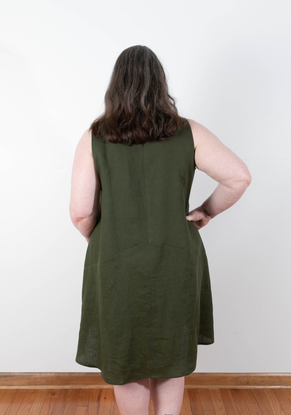 Back view of sleeveless Farrow Dress in solid olive linen showing center back seam and flared hem.