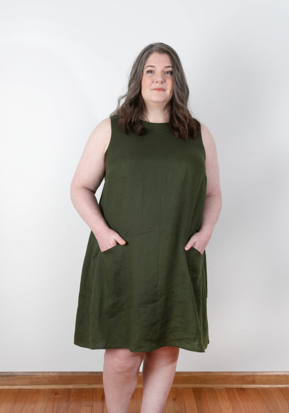 Front view of Farrow Dress in size 14-32, sleeveless version in solid olive linen with angled seam and pockets.