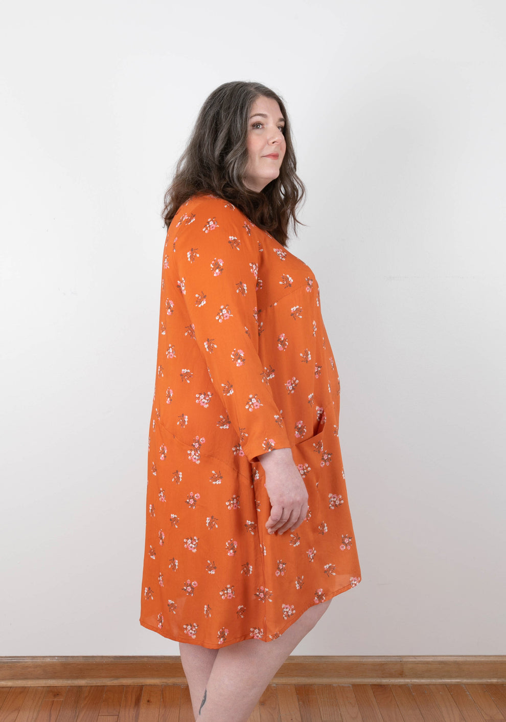 Side view of orange floral Farrow Dress with long sleeves and angled seam shaping.