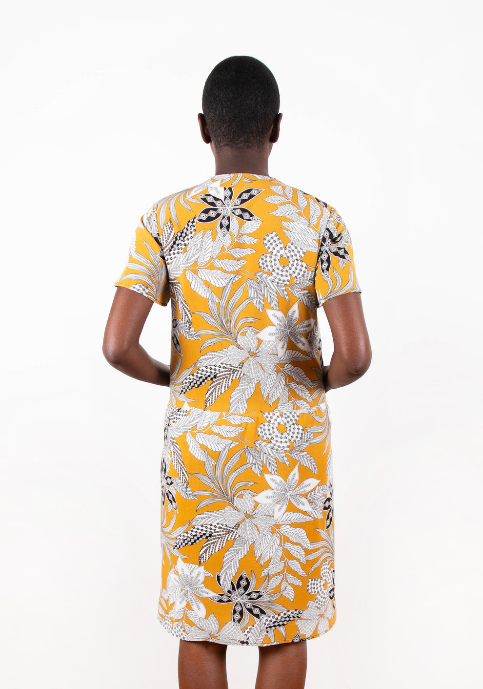 Back view of Felix Dress in yellow floral fabric, shown on model.