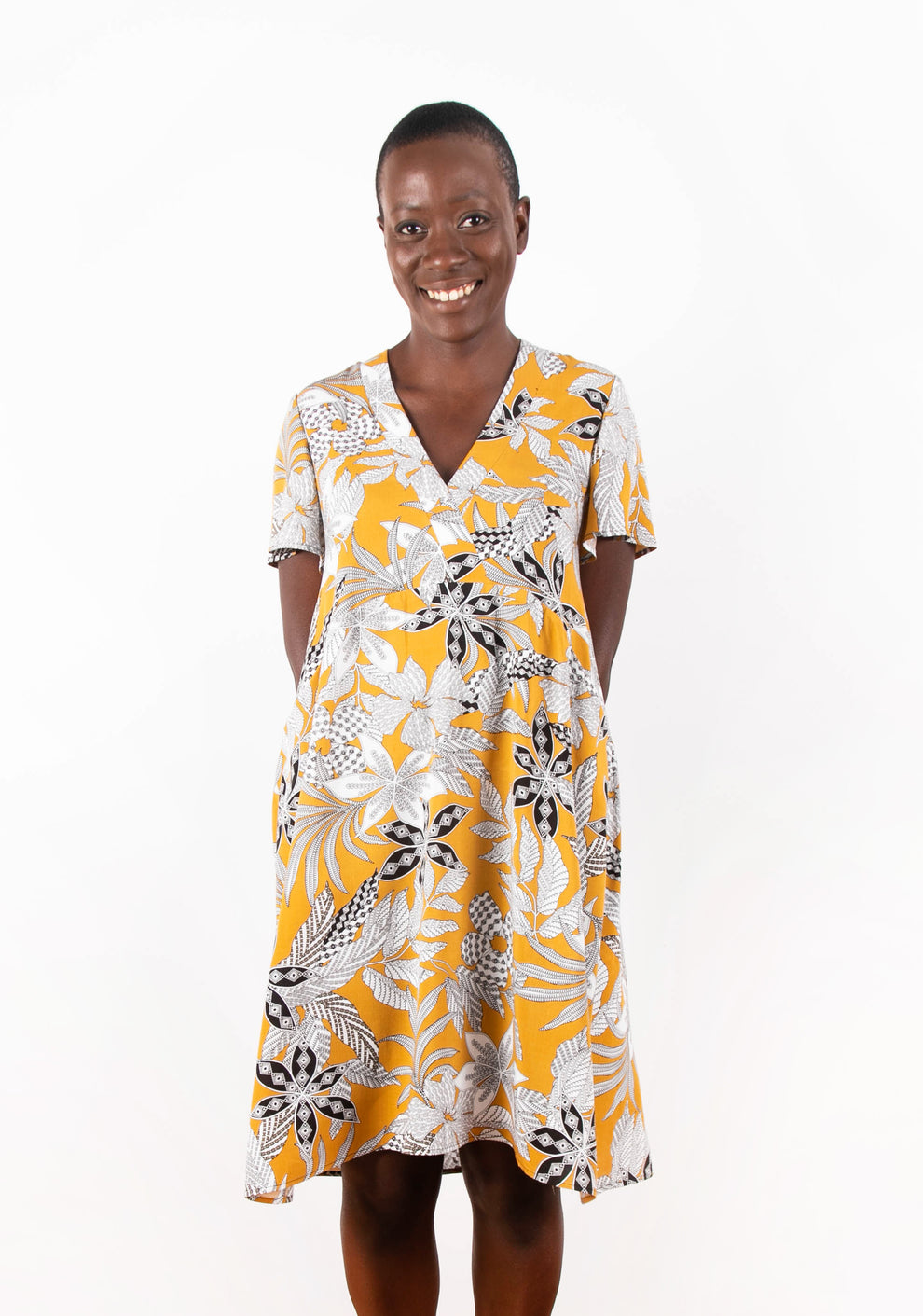 Model wearing Felix Dress in yellow floral fabric, front view with flutter sleeves.