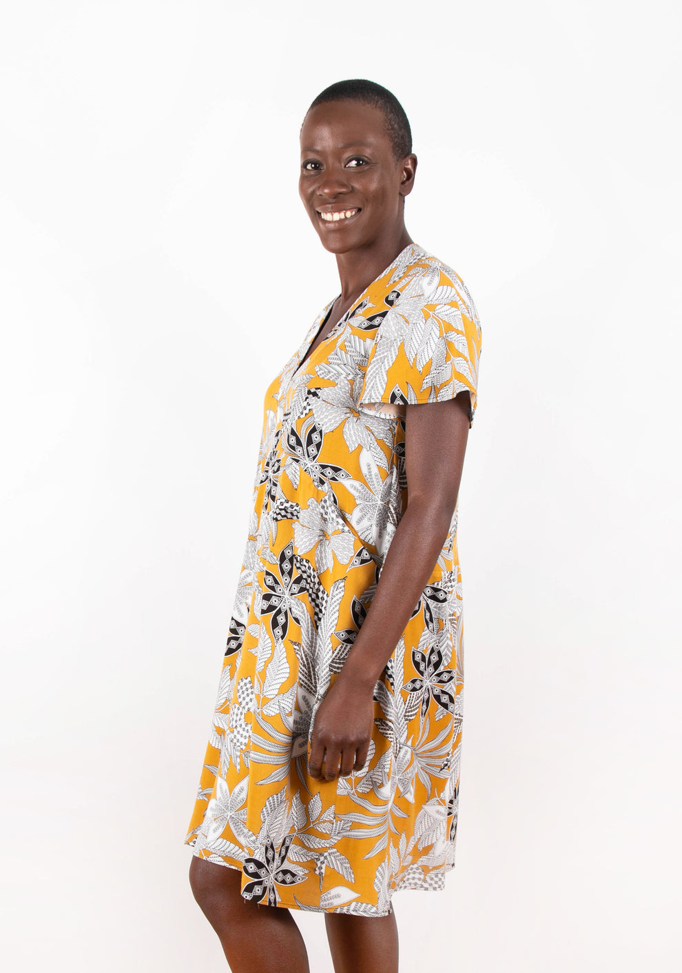 Side view of model wearing Felix Dress in yellow floral fabric with flutter sleeves.