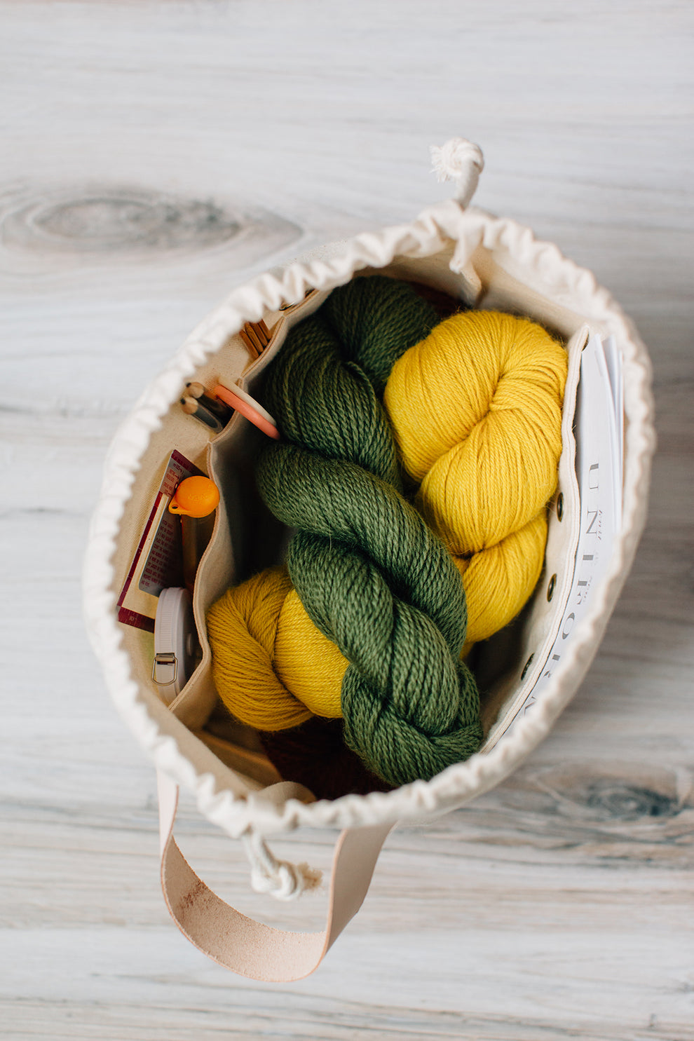 Interior view of natural field bag filled with yarn and knitting tools.