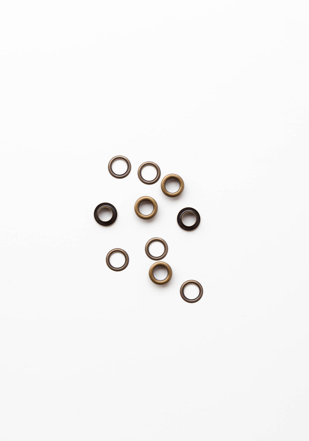 Flatlay of antique brass grommets for the Field Bag sewing pattern on a clean white background.