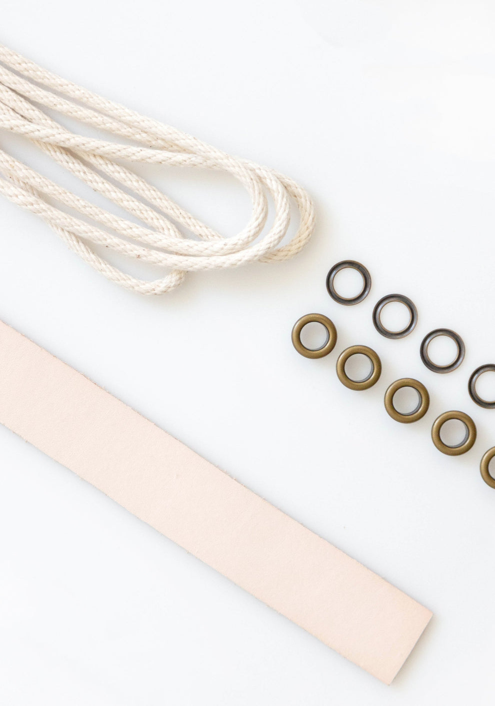 Angled view of Field Bag notions kit with natural leather strap, drawstring cord, and brass grommets on white surface.