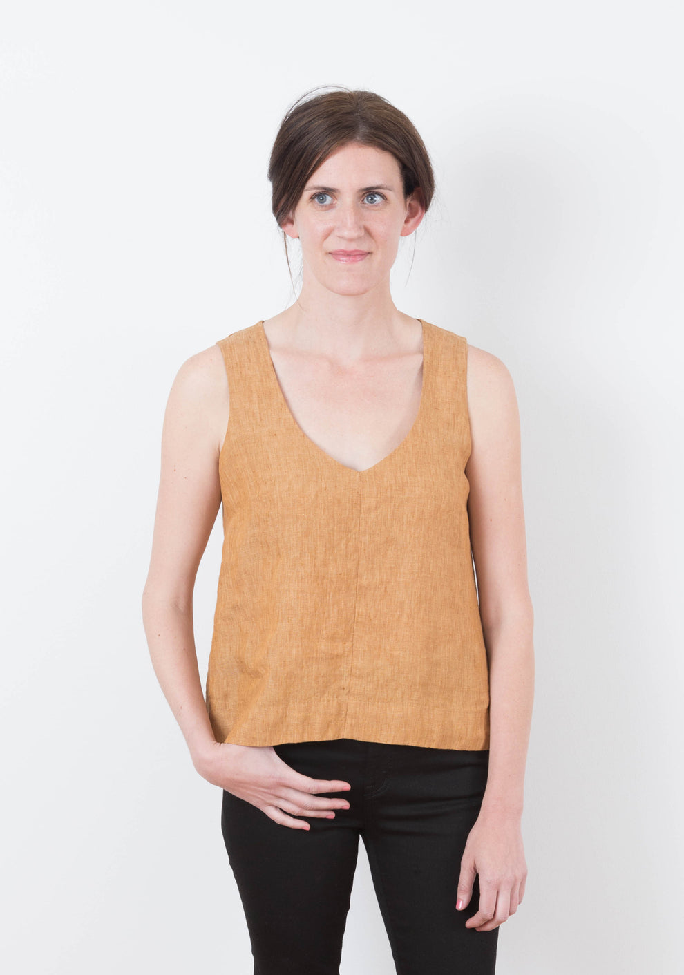 Front view of sleeveless Hadley Top in rust linen with V-neckline, worn by model.