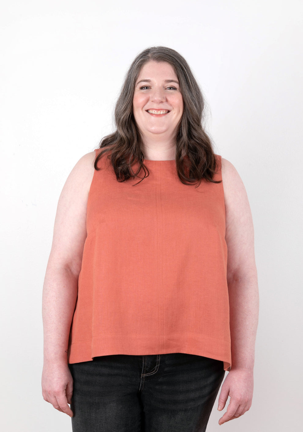 Model in sleeveless coral-colored Hadley Top, front view. Features scoop neckline and A-line fit.