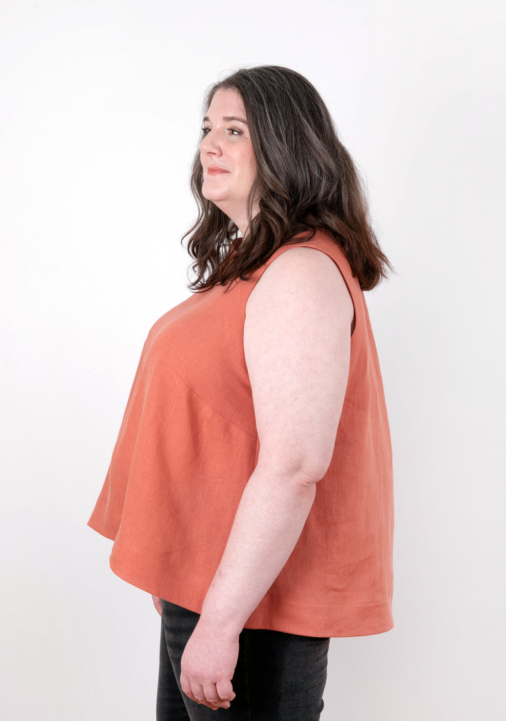 Model wearing sleeveless coral Hadley Top, side angle. Shows angled side seam and relaxed shape.