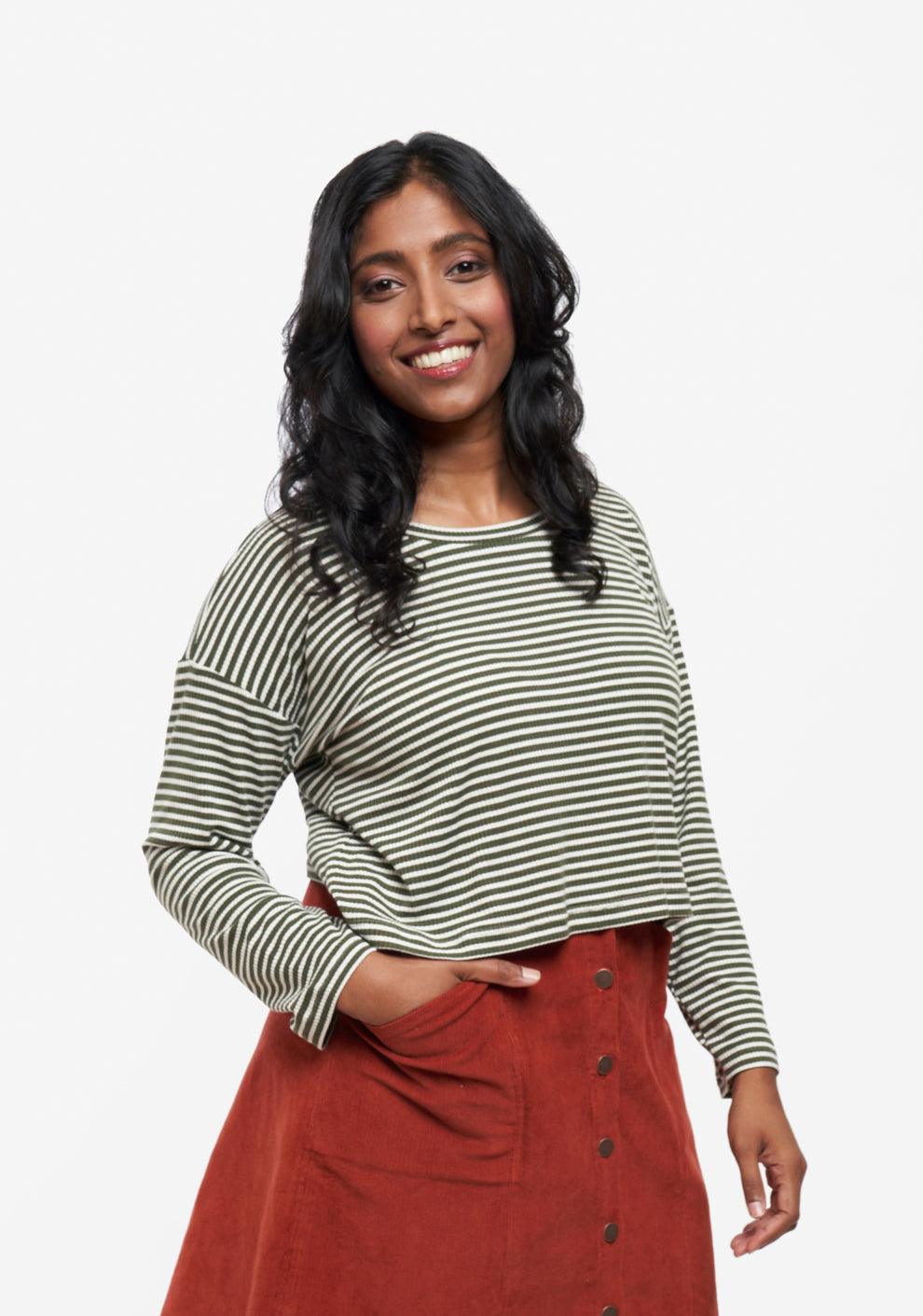 Model in cropped Hemlock Tee with long sleeves and stripes, worn with rust corduroy skirt.
