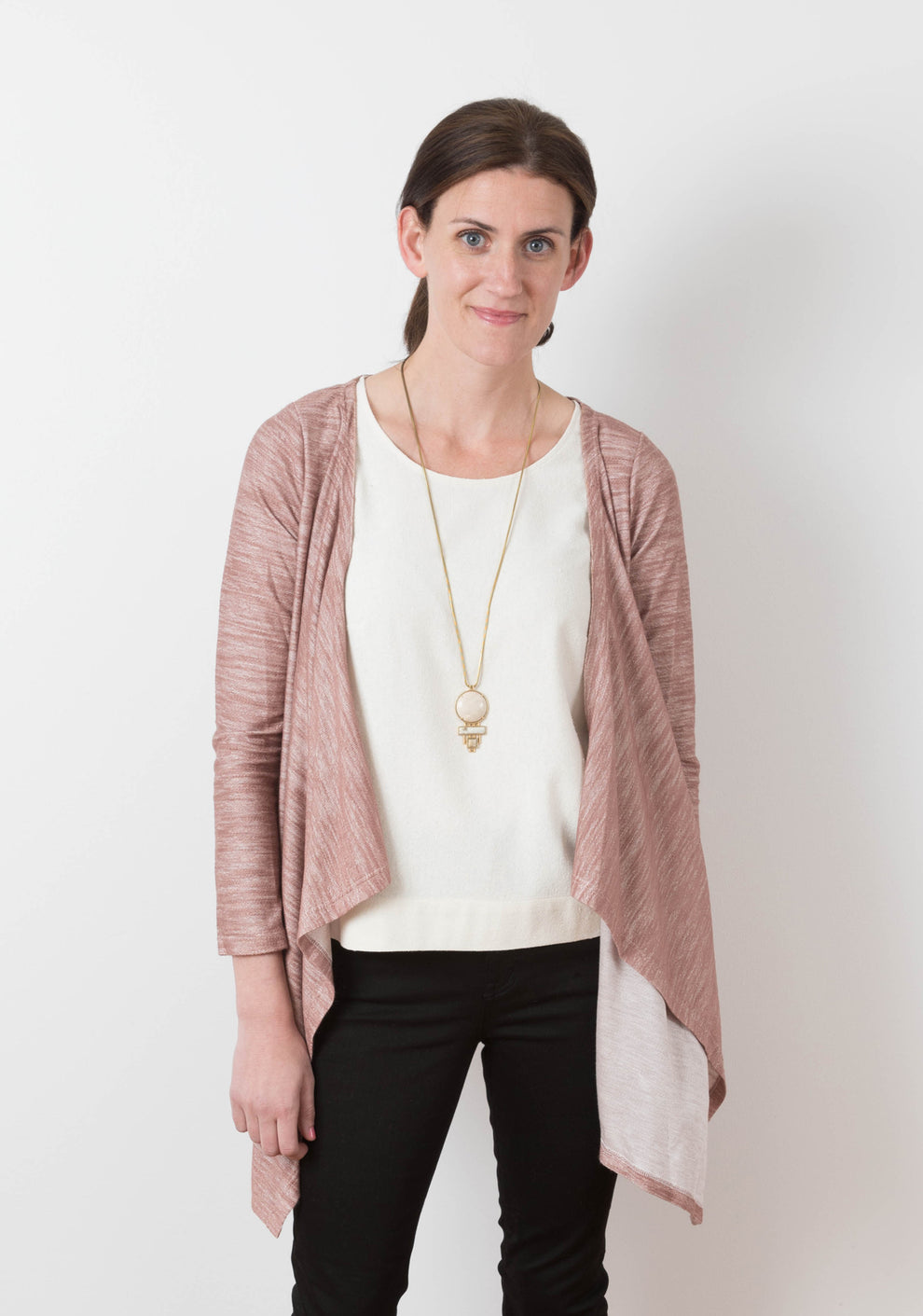 Model wearing rose-colored Lark Cardigan from front, showing necklace styling and waterfall hem.