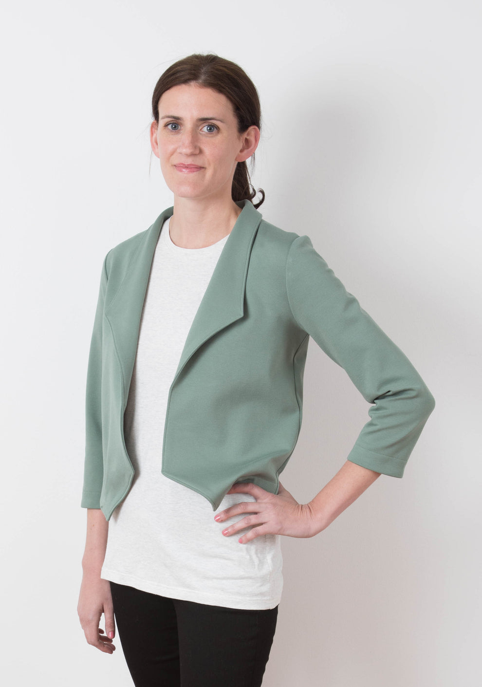 Model wearing Morris Blazer in sage ponte knit fabric, front view with hand on hip.