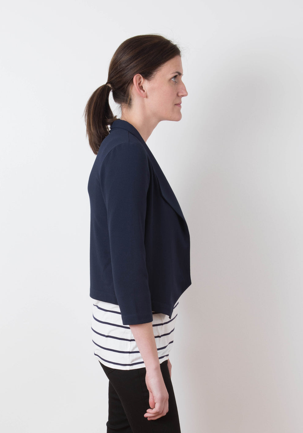 Model wearing Morris Blazer in navy stretch woven fabric, side view with striped tee visible underneath.