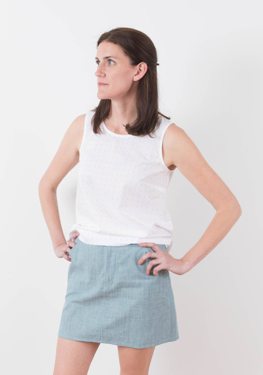 Front angled view of Moss Skirt in light blue chambray paired with sleeveless white top.