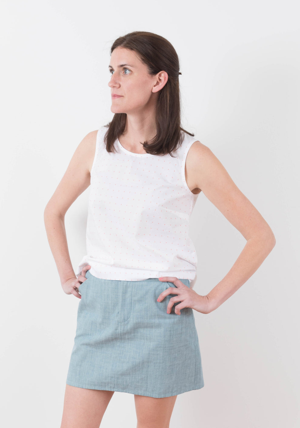 Front angled view of Moss Skirt in light blue chambray paired with sleeveless white top.
