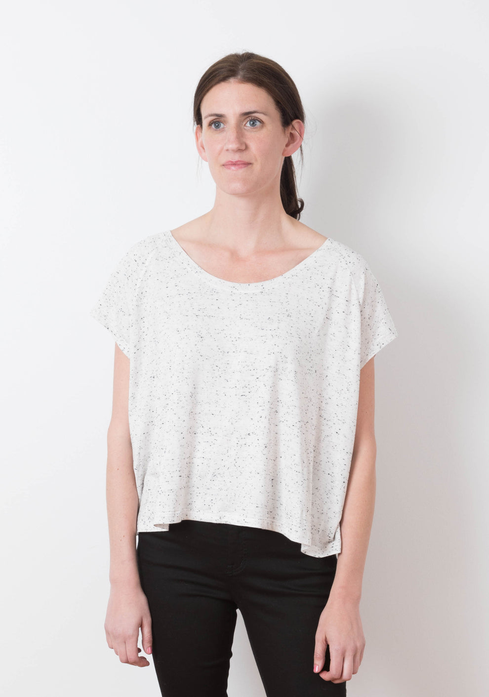 Front view of model wearing the Penny tee, a short sleeve knit top with a boxy silhouette and curved hem.