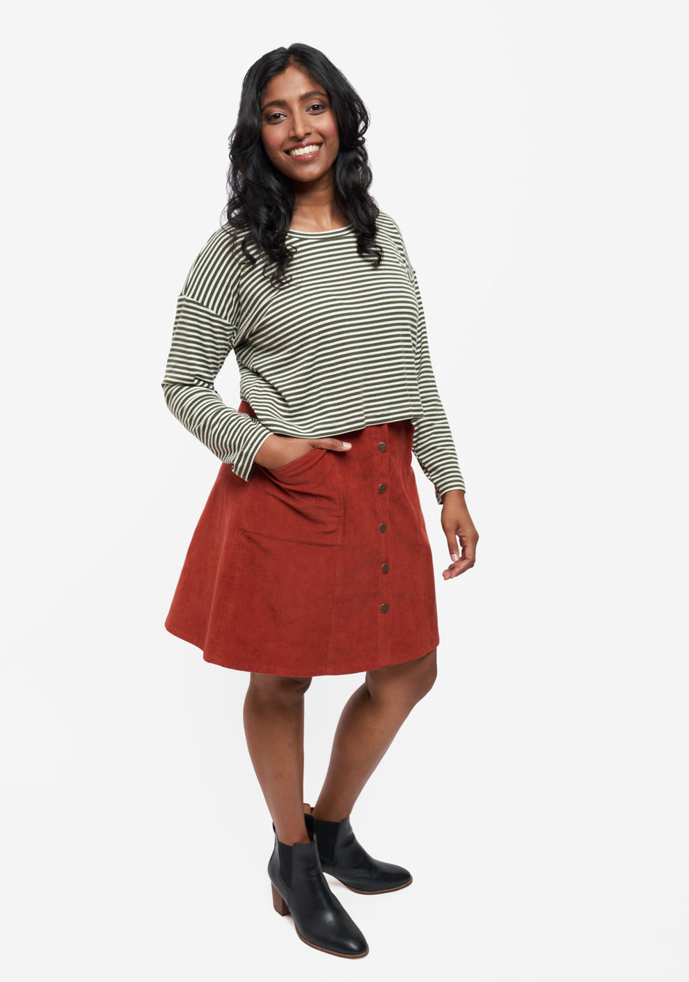 Angled front view of Reed Skirt in rust corduroy styled with striped top and black ankle boots.