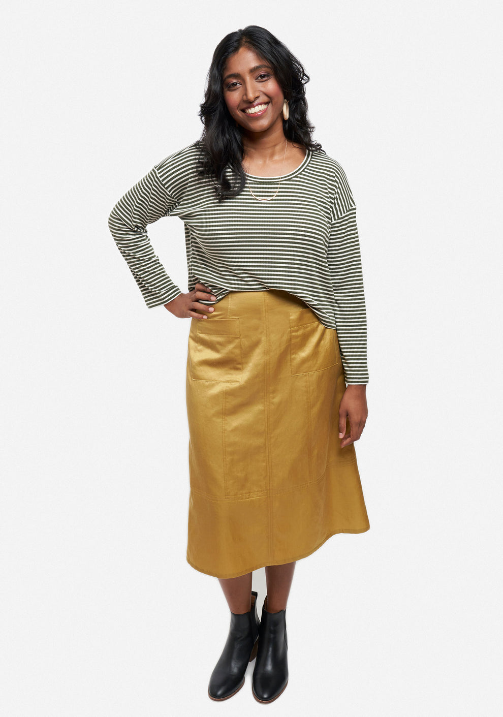 Front view of Reed Skirt in golden rayon with topstitched patch pockets, worn with striped top.