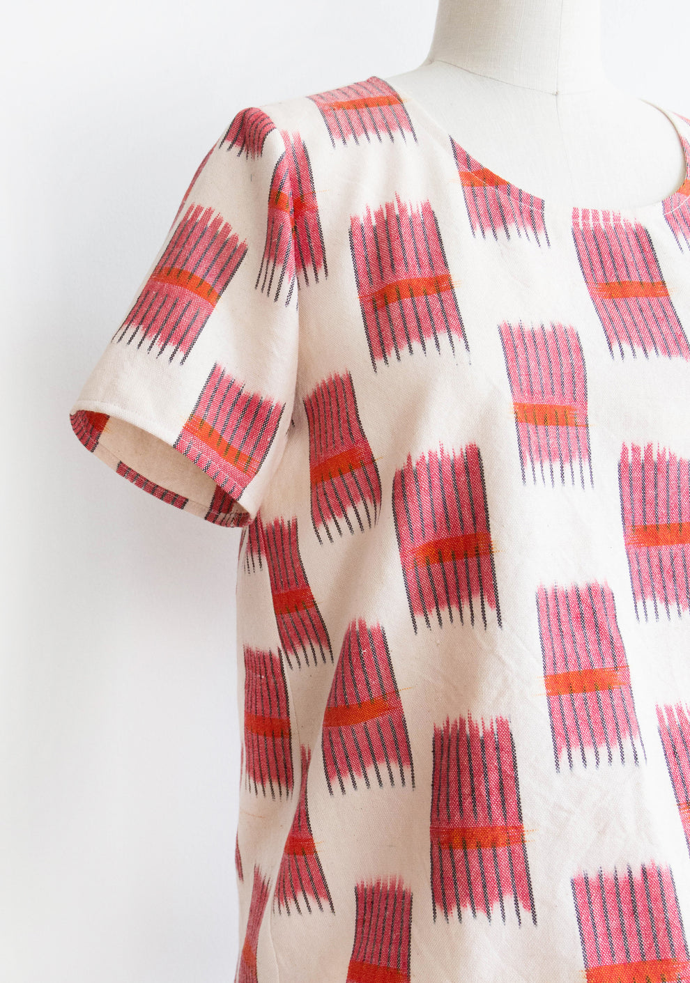 Close-up of Scout Tee cuffed sleeve add-on in red and white ikat cotton on dress form.