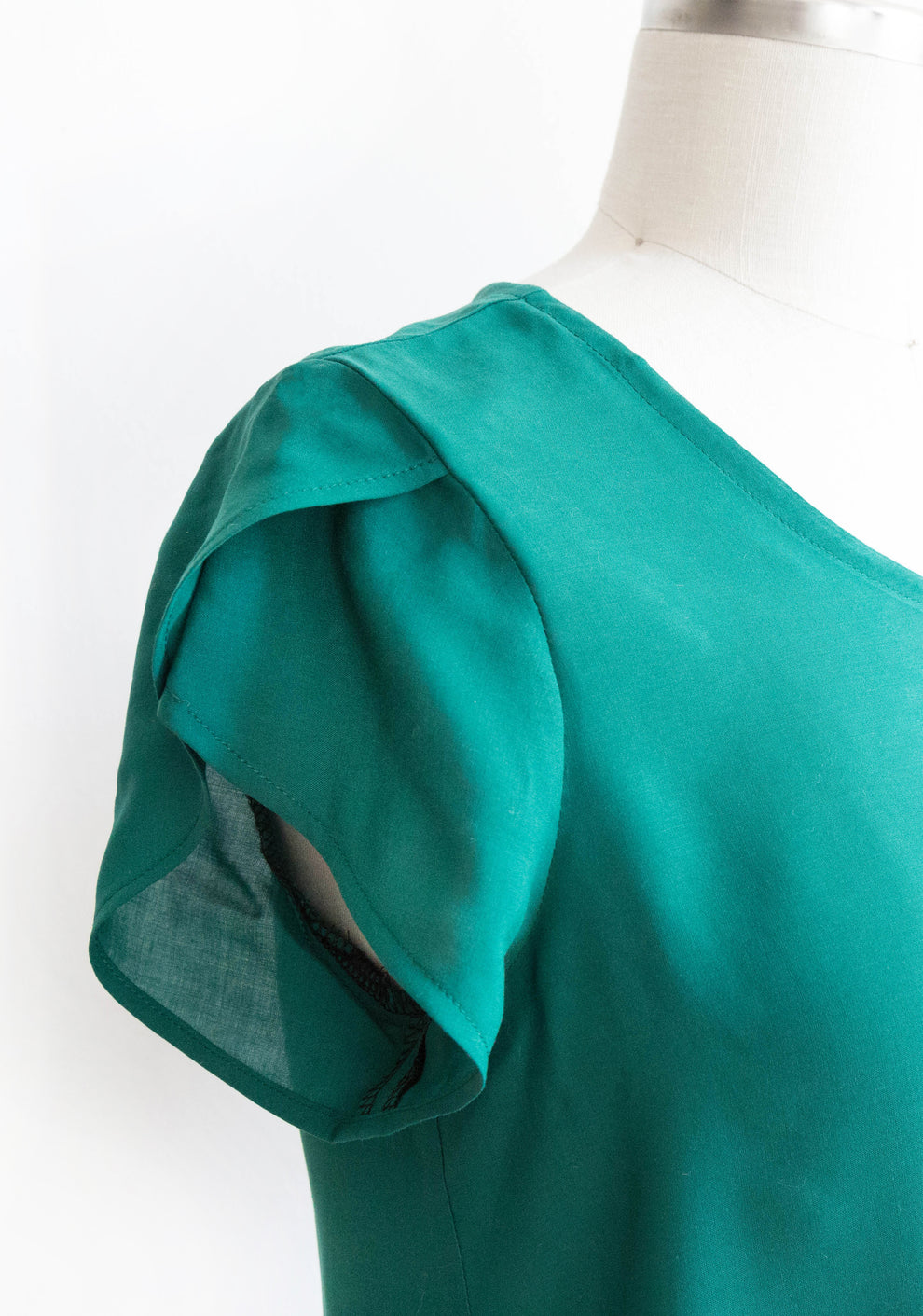 Close-up of Scout Tee petal sleeve add-on in green fabric on dress form.