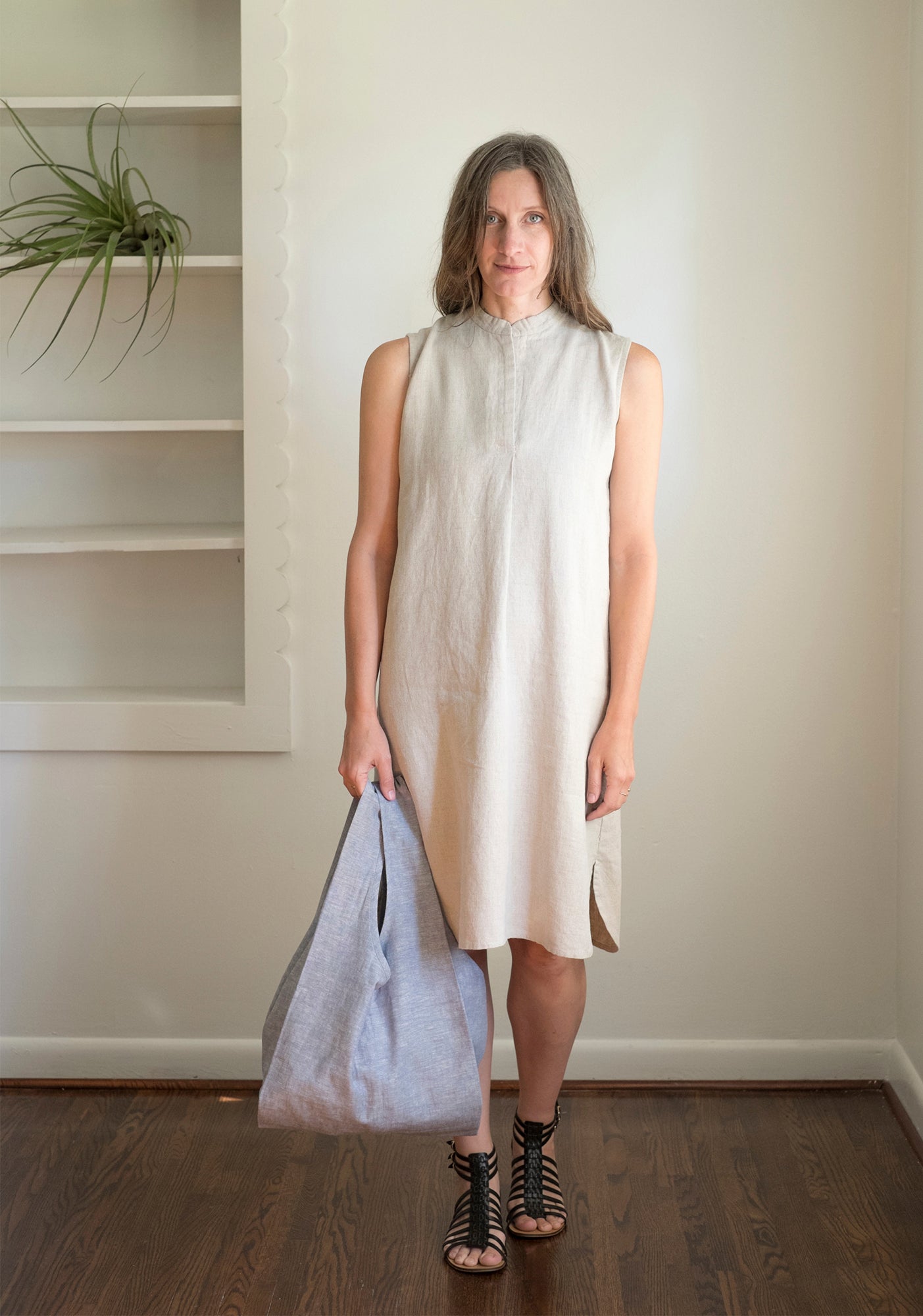 Person holding one large handmade Stowe Bags in blue chambray while standing indoors.