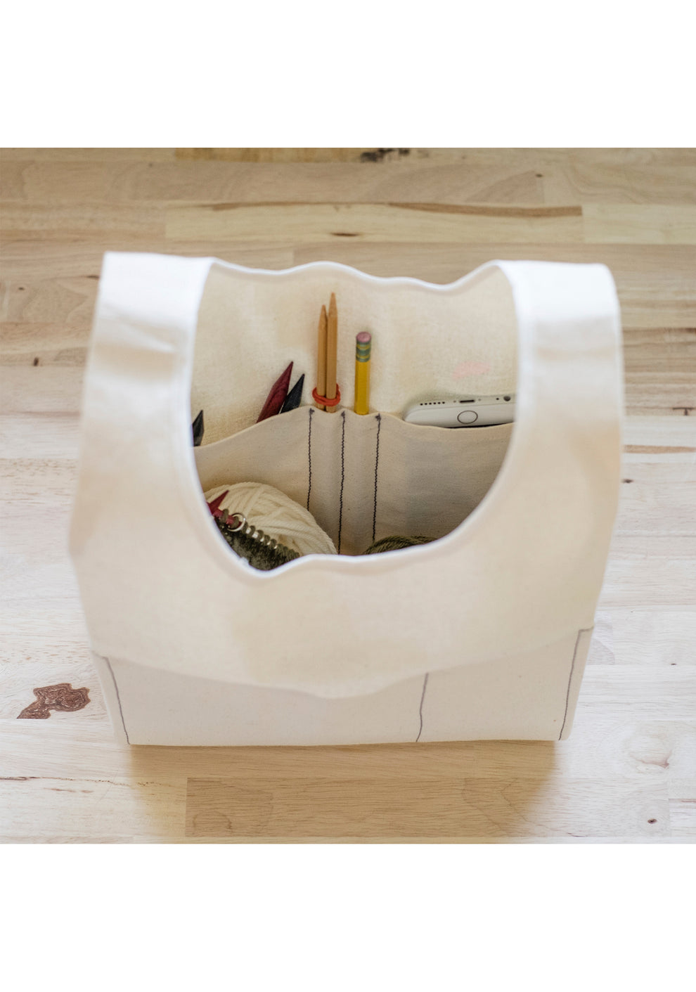 Top view of cream Stowe Bag with yarn, needles, and pencils in interior pockets.