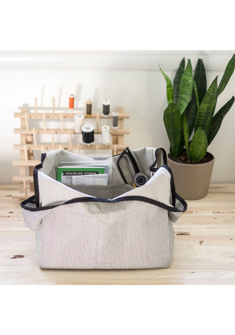 Striped Stowe Bag filled with sewing tools and supplies on a wooden work table.