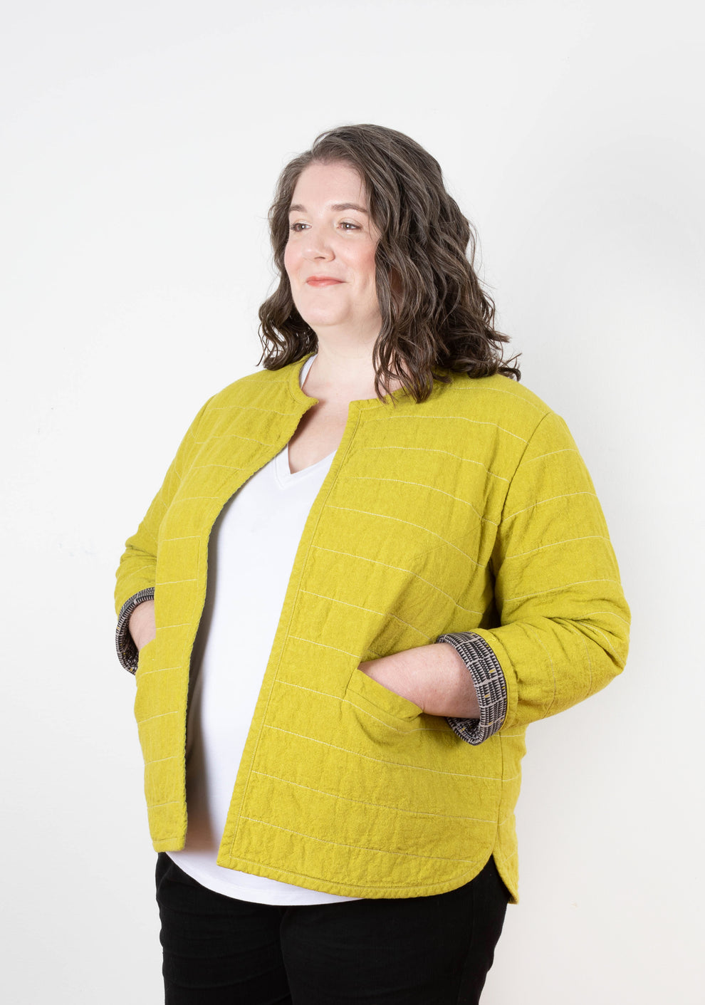 Three-quarter front view of Tamarack Jacket in mustard yellow linen, with visible quilting and front pockets.