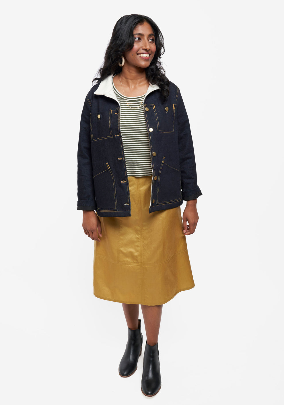 Model wearing Thayer Jacket over striped shirt and gold skirt with black ankle boots.