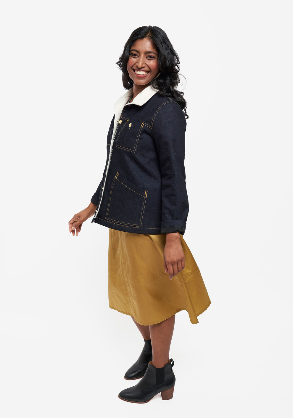 Side view of model in Thayer Jacket styled with gold skirt and black boots.