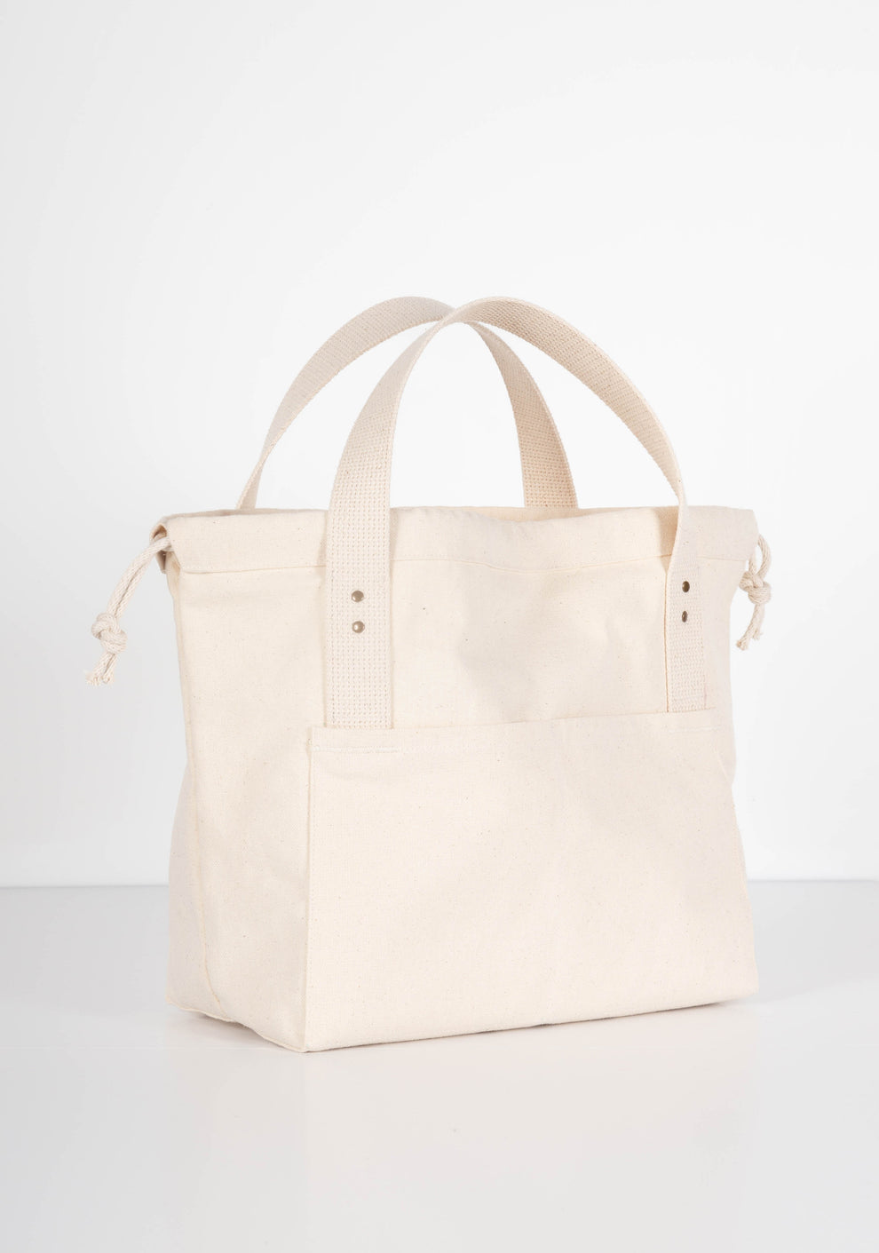 Natural canvas Town Bag, three-quarter front view with handles upright and drawstring open.