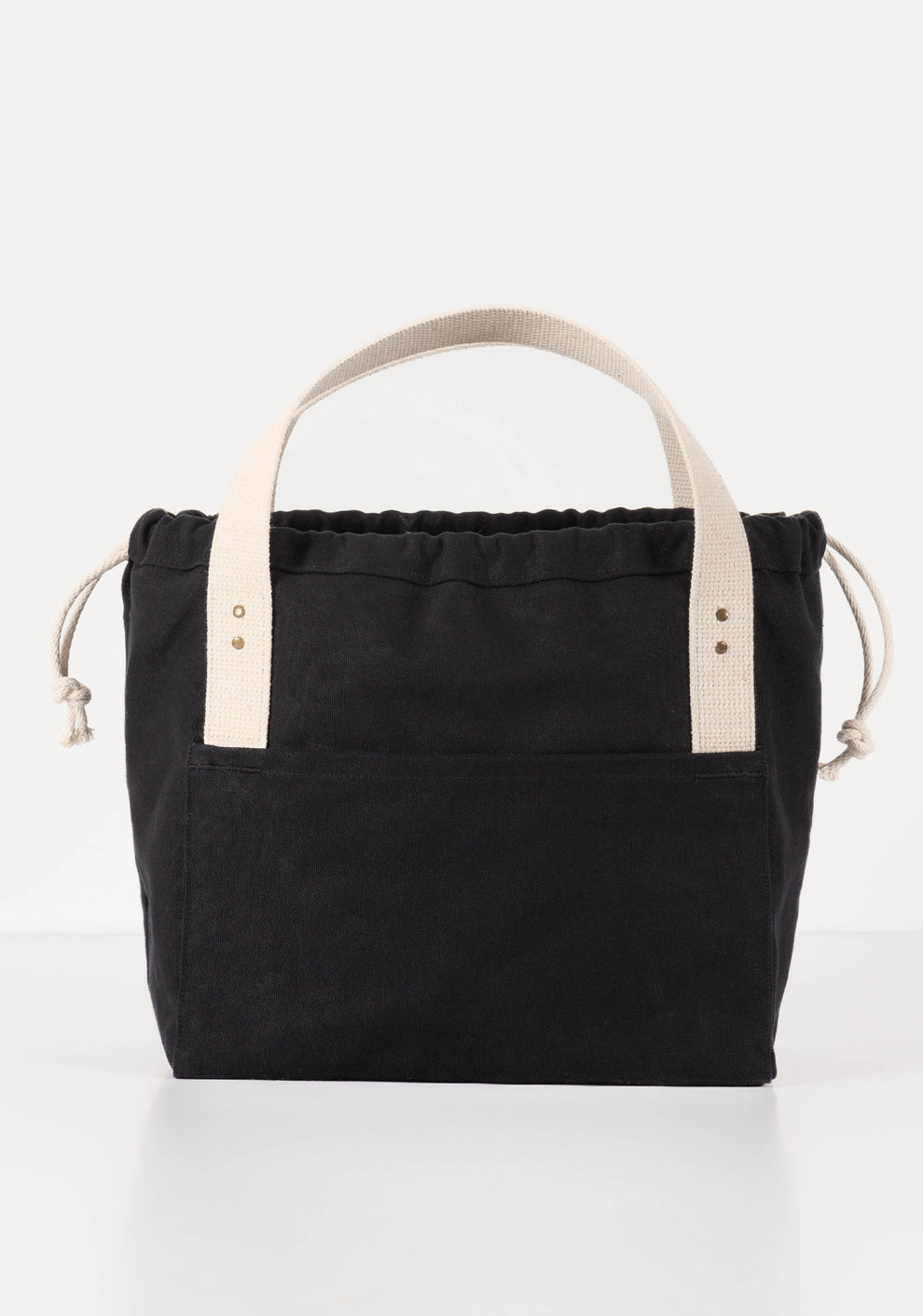 Front view of black canvas Town Bag with drawstring closed and white handles upright.