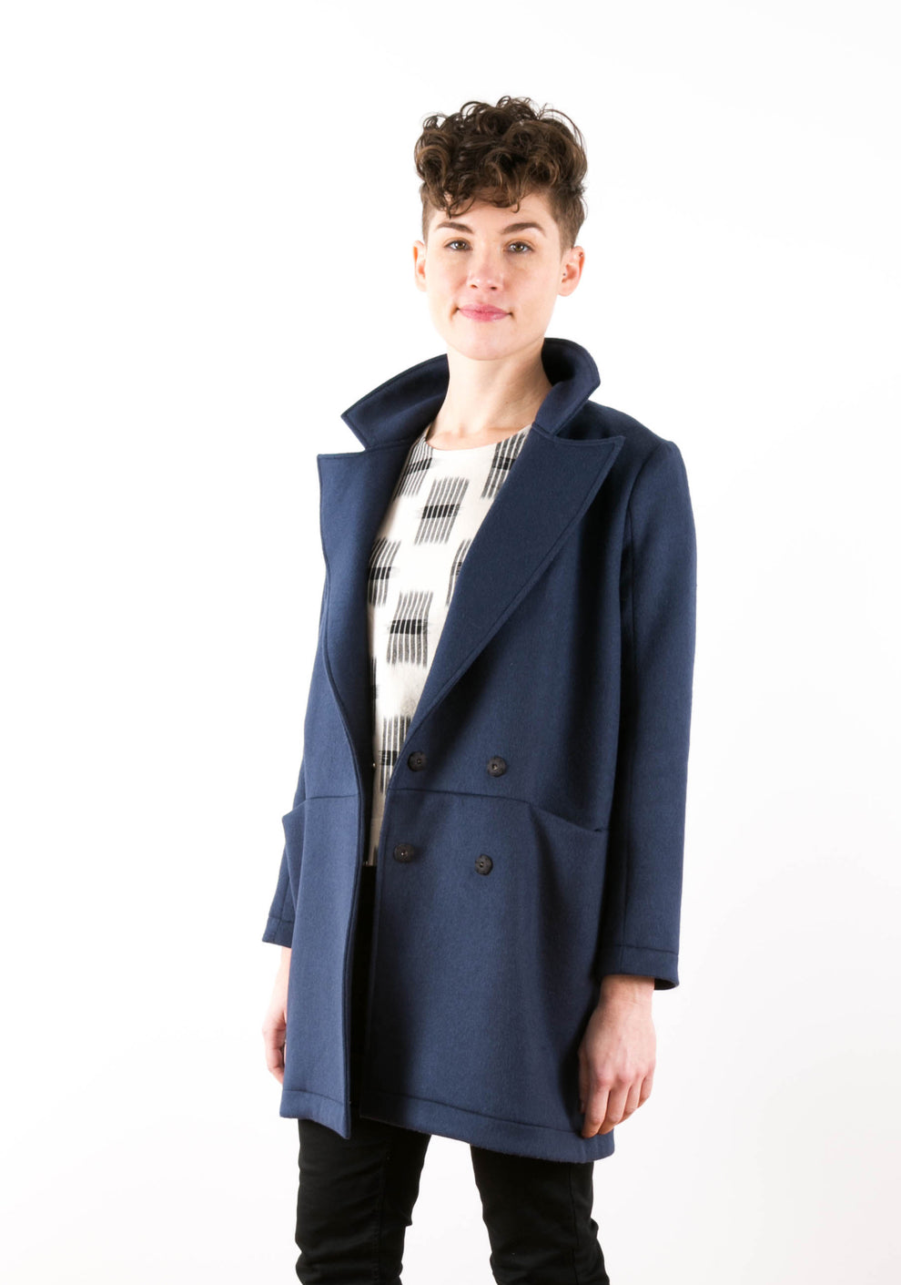 Three-quarter front view of model in navy Yates Coat with collar raised and double-breasted buttons visible.