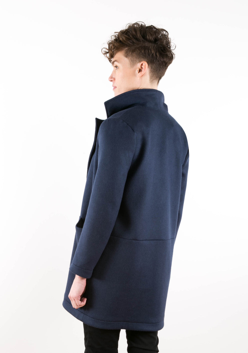 Back view of model in navy Yates Coat with raised collar and horizontal seam detail.