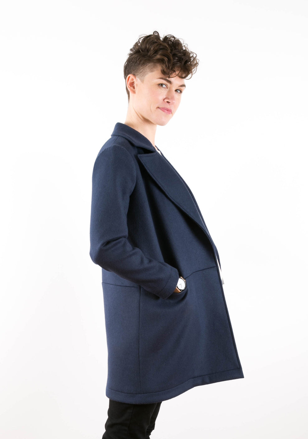 Model glancing over shoulder in side view of navy Yates Coat with deep patch pocket.